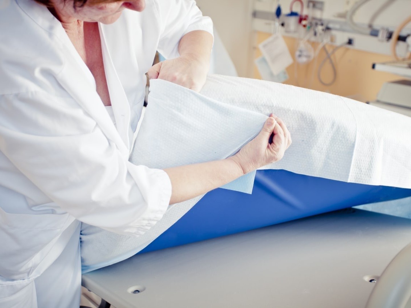A nurse covers a hospital bed with a maternity sheet developed by ASAP Norway.