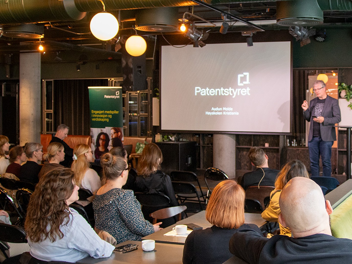 mann på scenen med mange folk i salen